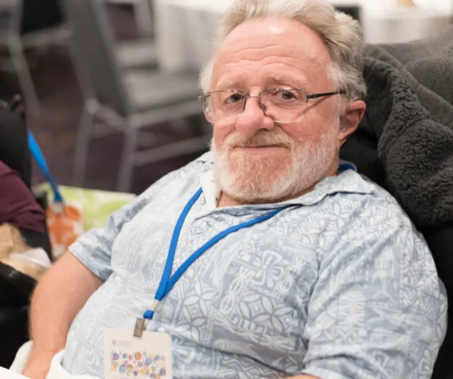 Elderly man sitting down looking at photographer